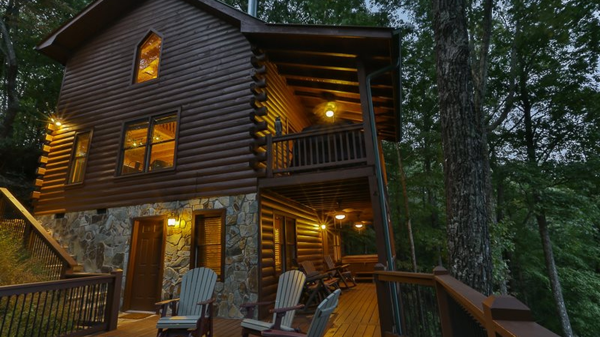 The cabin glows at dusk — warm lights, wood, and mountain quiet.